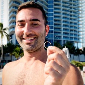 man holds a wedding ring on the beach after recovered with a metal detector