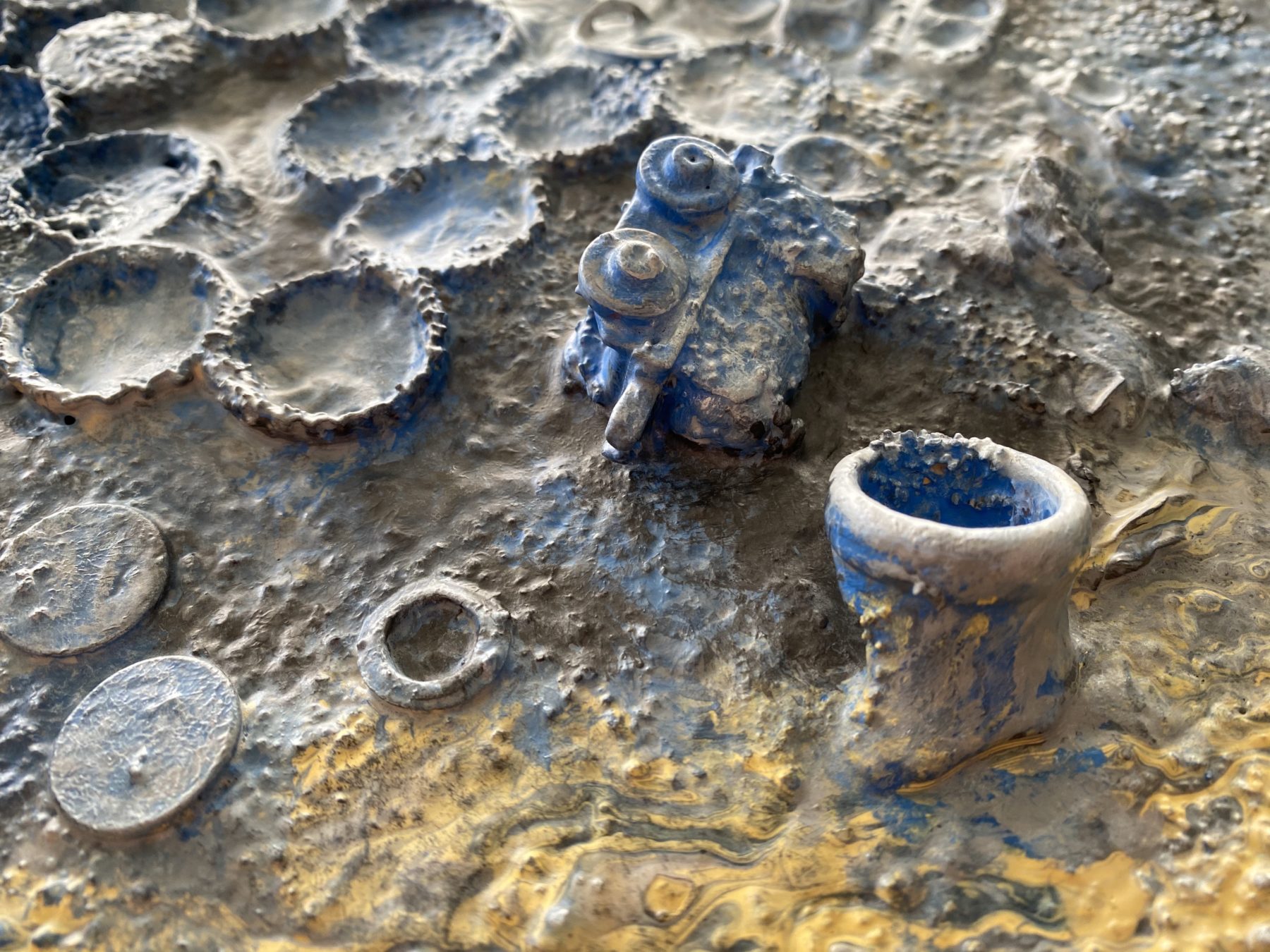 Detail of a toy train car and bottle caps from metal detecting artwork