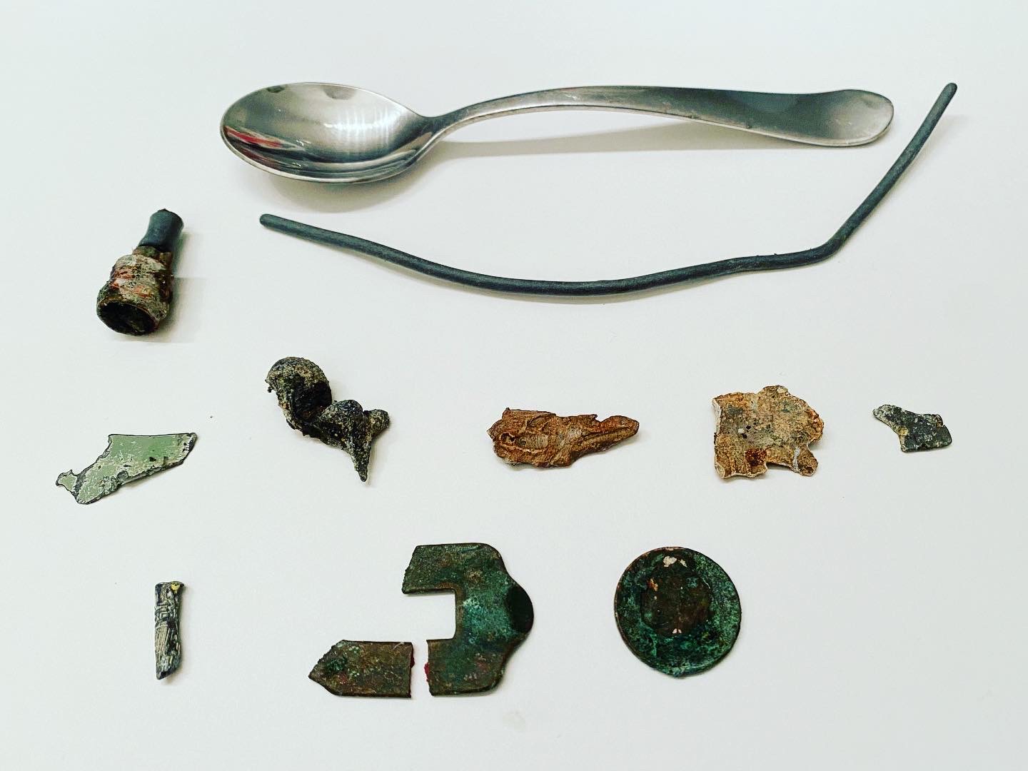 Beach metal detecting finds including a spoon, shoe buckle, and metal scraps