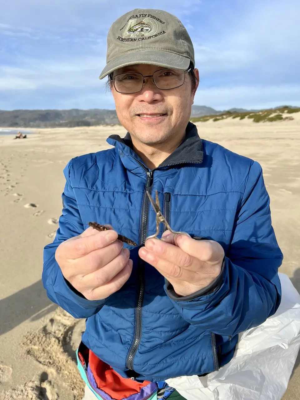Metal detecting lesson student holds up items found while searching the beach